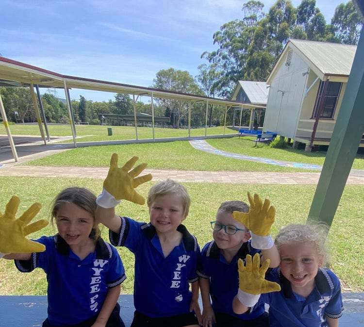 Image of four students holding their hands up.