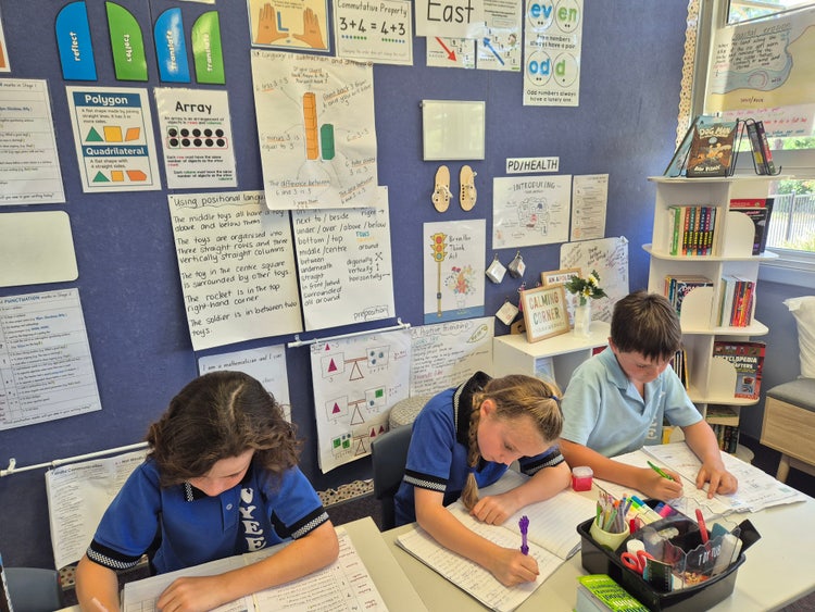 Image of three students working in their classroom.